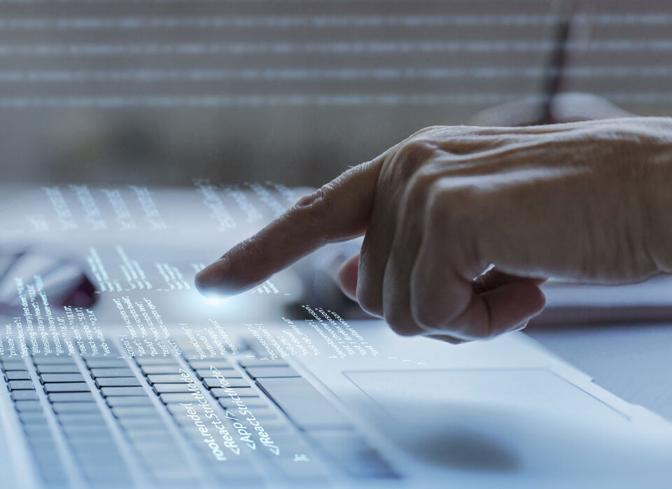 Mão interagindo com tela digital sobre teclado, representando automação e tecnologia na gestão digital de peças.