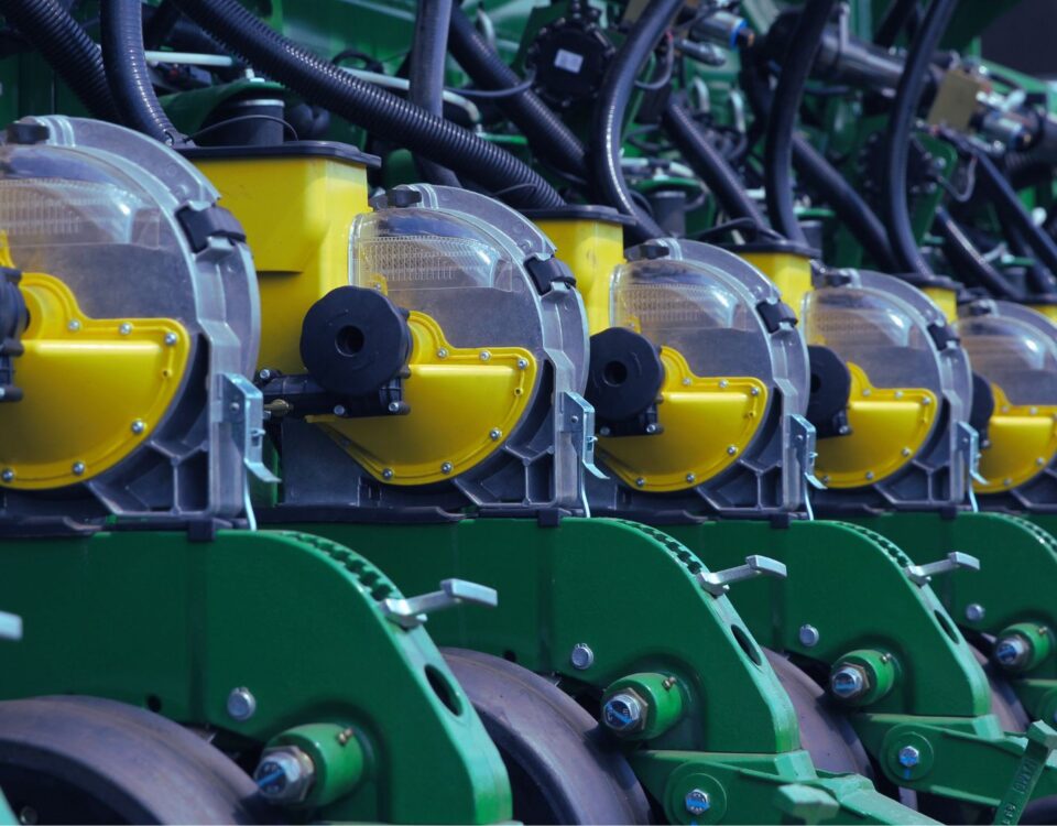 Máquinas agrícolas alinhadas em parque fabril, destacando componentes verdes e amarelos que simbolizam eficiência e economia circular na indústria